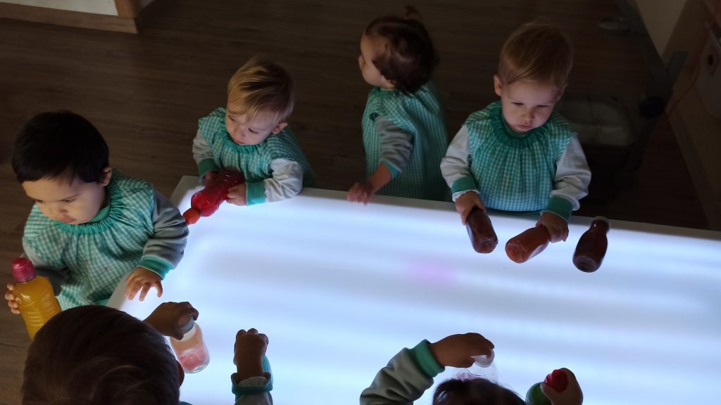 Alumnos en escuela infantil be you durante actividad con la mesa de luz y botellas sensoriales